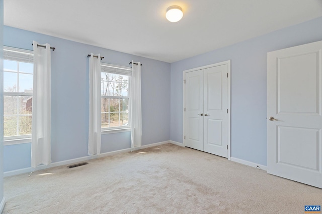 unfurnished bedroom with carpet, baseboards, a closet, and visible vents