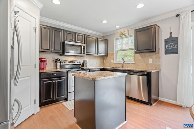kitchen with a sink, light wood finished floors, stainless steel appliances, and decorative backsplash