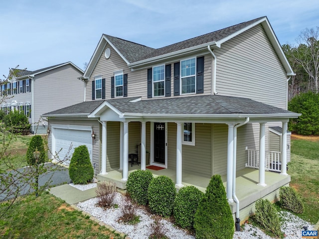 traditional-style home with covered porch, an attached garage, and a shingled roof