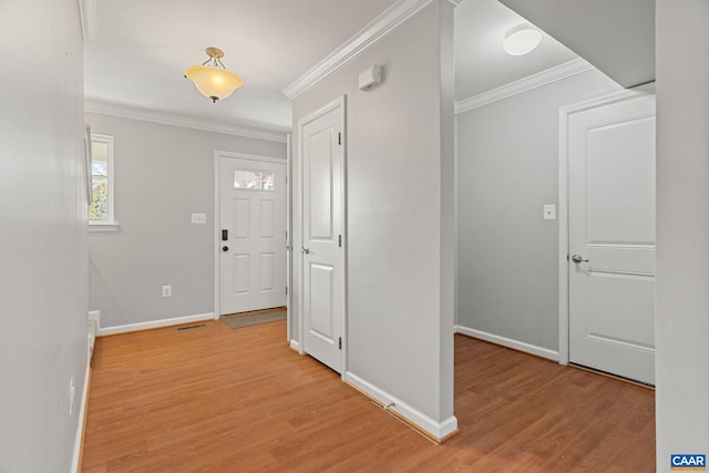 foyer entrance with crown molding, light wood-style flooring, baseboards, and visible vents
