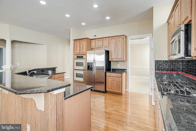 5409 Rich Mountain Way E, Fredericksburg, VA 22407 - kitchen with stainless steel appliances, a sink, a kitchen breakfast bar, light wood-style flooring, and decorative columns