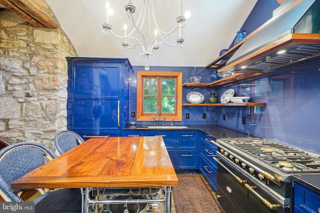 kitchen with range with two ovens, blue cabinetry, a sink, ventilation hood, and dark countertops