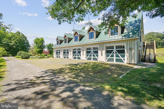 view of front of property featuring board and batten siding, driveway, stairway, metal roof, and a front yard