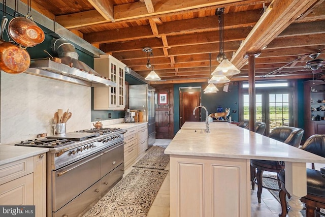 kitchen with premium appliances, a sink, wooden ceiling, beam ceiling, and a kitchen bar