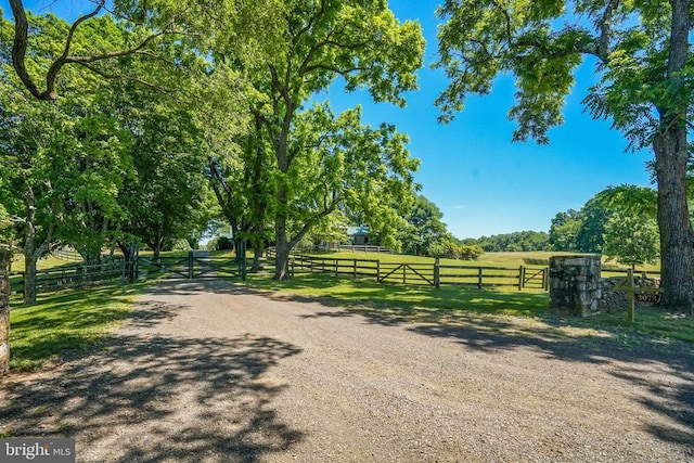 view of dirt / gravel road with a rural view and a gate