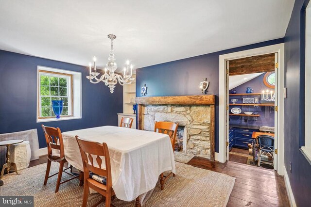 dining area featuring a chandelier, hardwood / wood-style floors, a fireplace, and baseboards