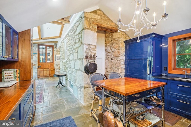 dining space featuring stone tile flooring, vaulted ceiling, and a chandelier