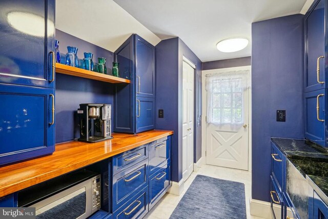 bar area featuring stainless steel microwave and baseboards
