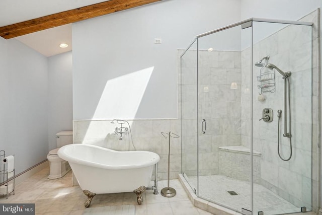 bathroom with a stall shower, a freestanding tub, tile patterned flooring, toilet, and a wainscoted wall