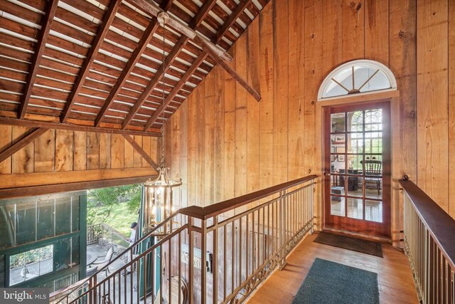 hall featuring wood walls, wood finished floors, wood ceiling, and high vaulted ceiling