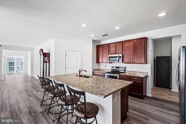 6607 Golden Pheasant Run, Fredericksburg, VA 22407 - kitchen with stainless steel appliances, a sink, dark wood-style flooring, a center island with sink, and a breakfast bar area