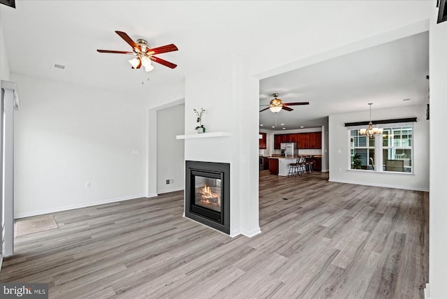 6607 Golden Pheasant Run, Fredericksburg, VA 22407 - unfurnished living room featuring a ceiling fan, a glass covered fireplace, light wood-type flooring, and a chandelier
