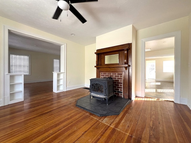 living room with ceiling fan, a wood stove, and dark hardwood / wood-style flooring