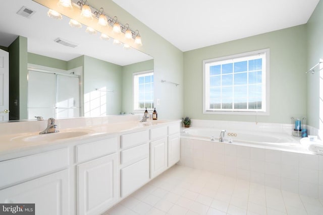 bathroom with double vanity, a garden tub, visible vents, and a sink