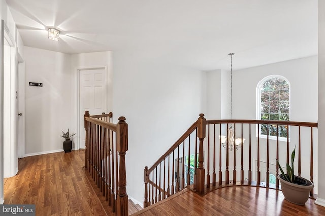  - corridor featuring an upstairs landing, wood finished floors, and a chandelier