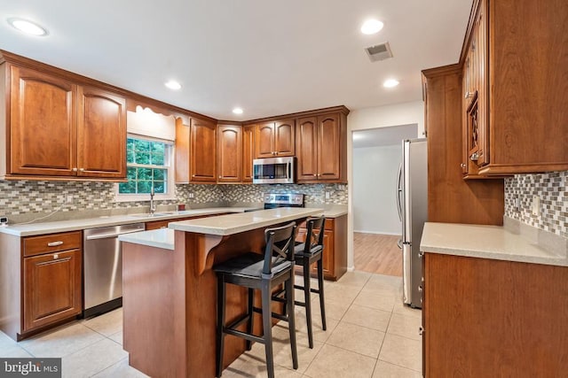  - kitchen with appliances with stainless steel finishes, backsplash, a breakfast bar, light tile patterned floors, and recessed lighting