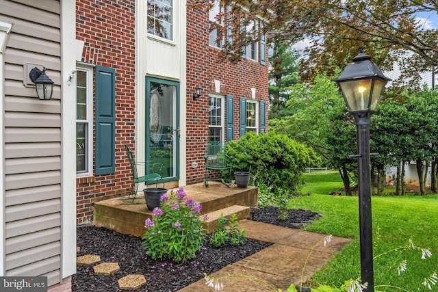  - property entrance featuring brick siding and a yard