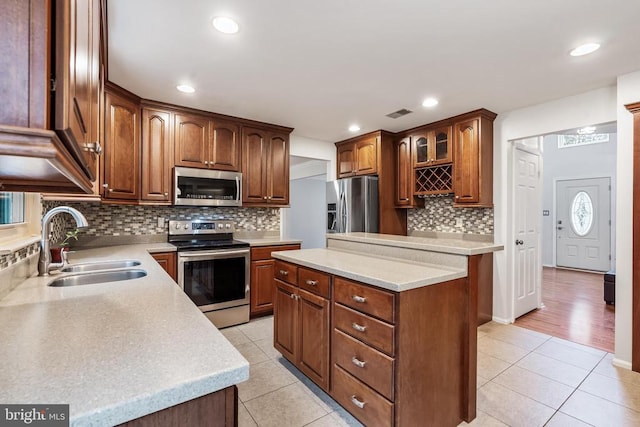  - kitchen with appliances with stainless steel finishes, light tile patterned flooring, backsplash, a kitchen island, and recessed lighting