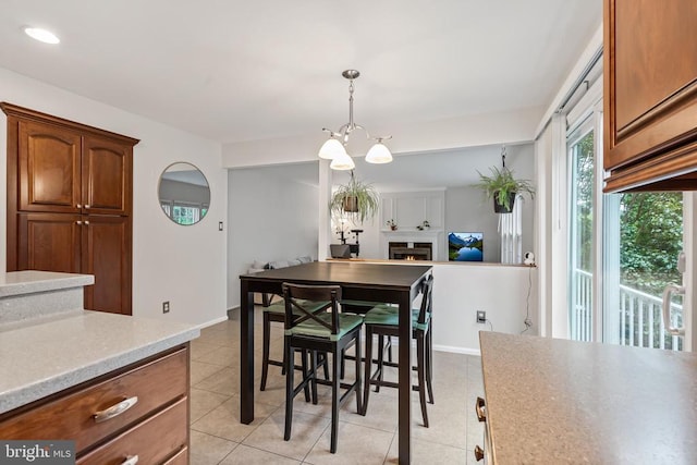  - dining space featuring a chandelier, light tile patterned flooring, and a warm lit fireplace