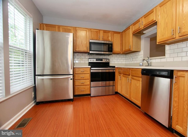 4605 Club Cart Cir, Fredericksburg, VA 22408 - kitchen with stainless steel appliances, light countertops, light wood-type flooring, and backsplash