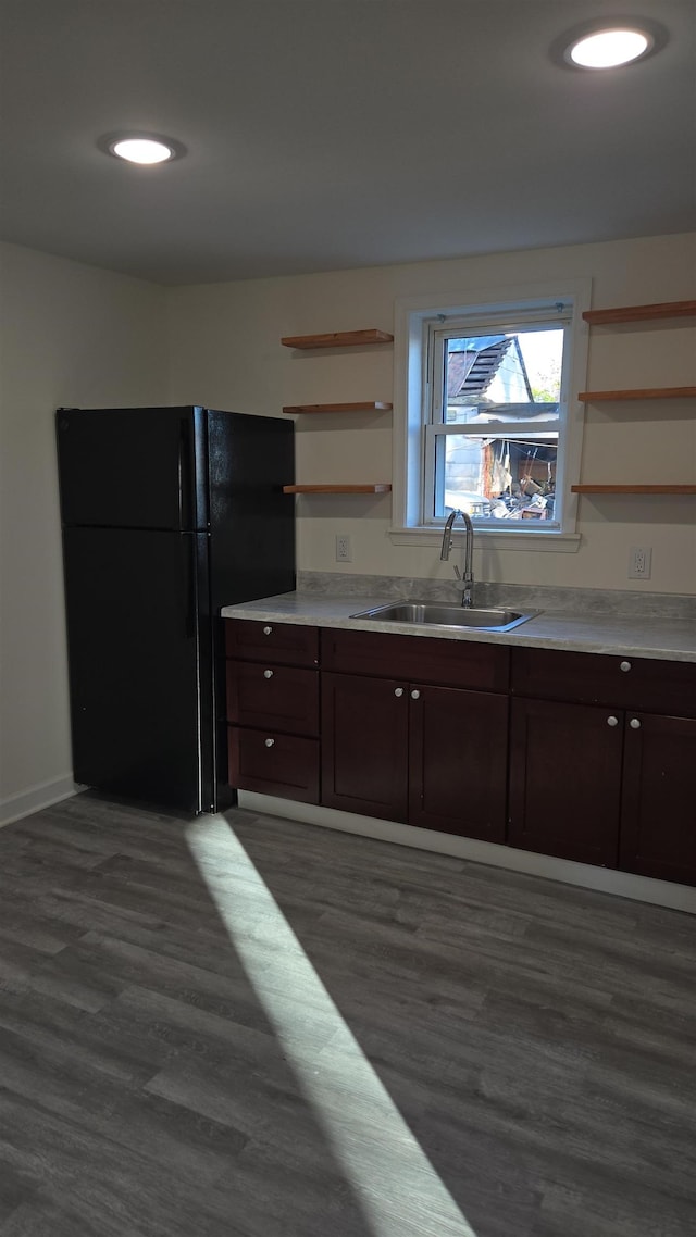 kitchen with freestanding refrigerator, a sink, open shelves, dark wood finished floors, and dark brown cabinets