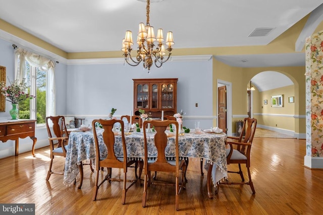  - dining space featuring a chandelier, wood finished floors, and arched walkways
