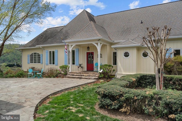  - view of front of property featuring a shingled roof and a patio