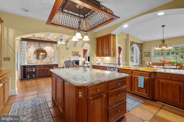  - kitchen featuring arched walkways, a sink, a chandelier, a kitchen island, and dishwasher