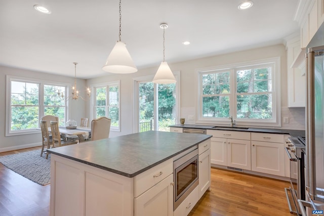 kitchen featuring an inviting chandelier, a sink, dark countertops, white cabinetry, and appliances with stainless steel finishes