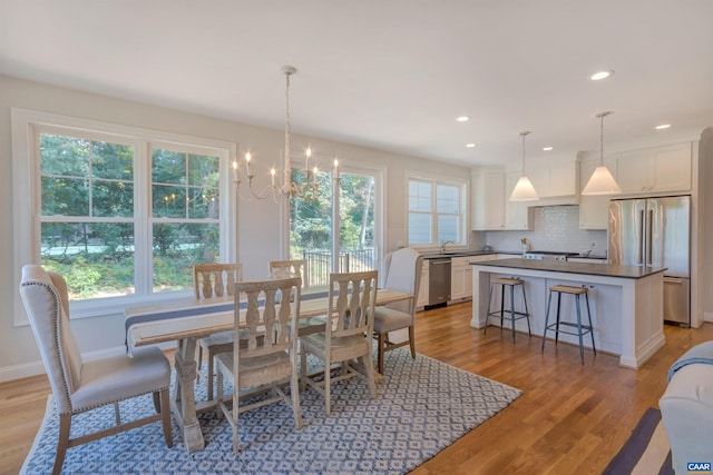 dining room with baseboards, an inviting chandelier, recessed lighting, and light wood-style flooring