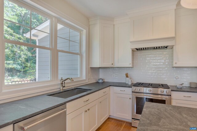 kitchen featuring a sink, white cabinetry, dark countertops, tasteful backsplash, and appliances with stainless steel finishes