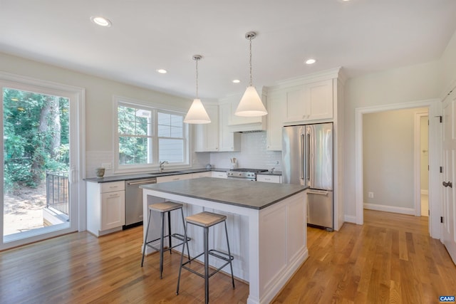 kitchen featuring a breakfast bar area, white cabinetry, backsplash, dark countertops, and appliances with stainless steel finishes