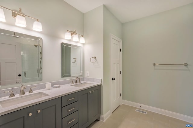 full bathroom with a shower stall, baseboards, double vanity, and a sink