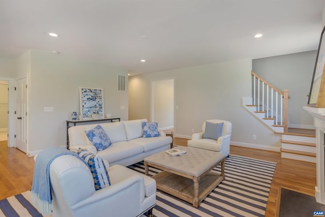 living area featuring light wood-style flooring, visible vents, baseboards, stairway, and recessed lighting