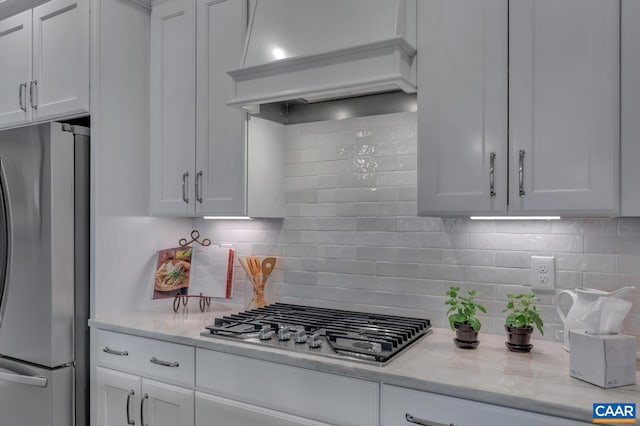 kitchen featuring white cabinets, appliances with stainless steel finishes, premium range hood, and tasteful backsplash