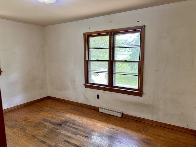 spare room with wood-type flooring, a baseboard radiator, and baseboards