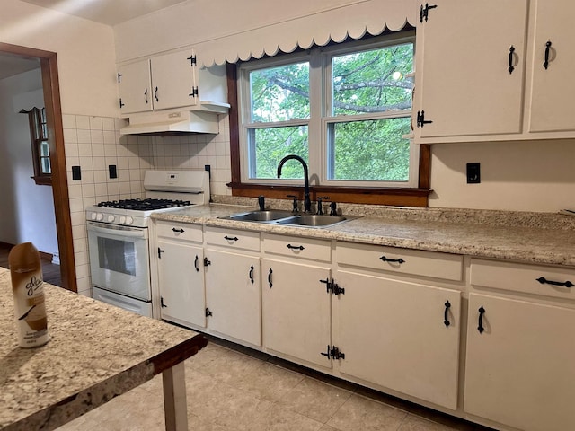 kitchen featuring white gas range oven, under cabinet range hood, a sink, light countertops, and white cabinets