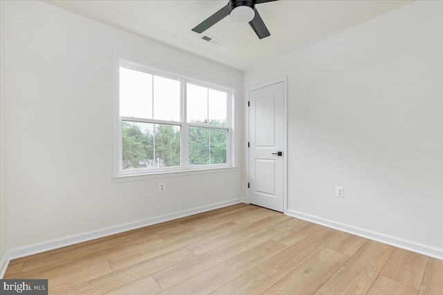 empty room with light wood-type flooring, a ceiling fan, and baseboards