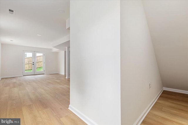 hall featuring light wood-style flooring, baseboards, and french doors