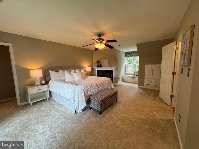  - carpeted bedroom featuring a fireplace, baseboards, and a ceiling fan