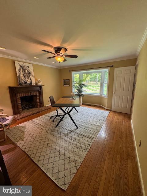  - office area featuring hardwood / wood-style flooring, a fireplace, crown molding, baseboards, and ceiling fan