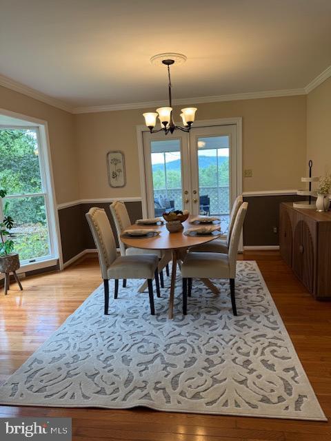  - dining area with light wood finished floors, a chandelier, and crown molding
