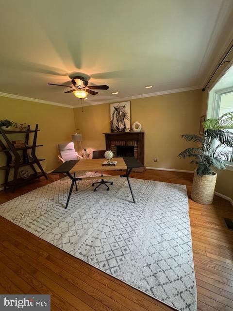  - sitting room featuring baseboards, wood finished floors, ceiling fan, ornamental molding, and a brick fireplace