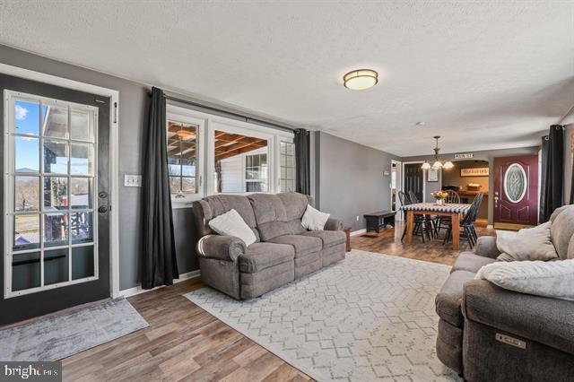 885 Main St W, Stanley, VA 22851 - living area featuring a chandelier, wood finished floors, baseboards, and a textured ceiling