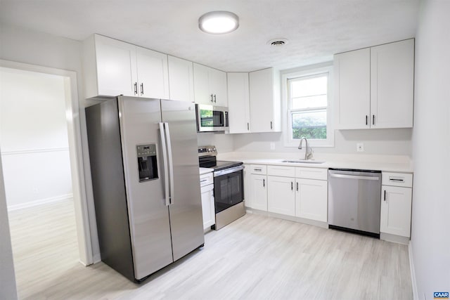 158 Scarborough Pl, Charlottesville, VA 22903 - kitchen featuring appliances with stainless steel finishes, light wood-type flooring, white cabinets, and light countertops