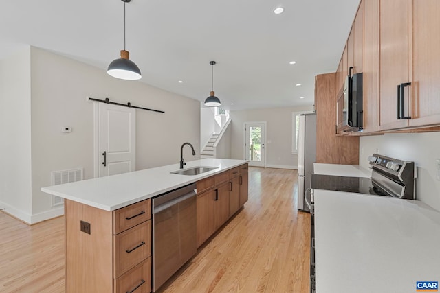 34 Turkeysag Trl, Palmyra, VA 22963 - kitchen featuring stainless steel appliances, a barn door, light wood-style flooring, an island with sink, and light countertops