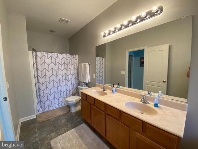 6029 Lost Cove Dr, Mineral, VA 23117 - full bathroom with stone finish floors, double vanity, toilet, a shower with shower curtain, and baseboards