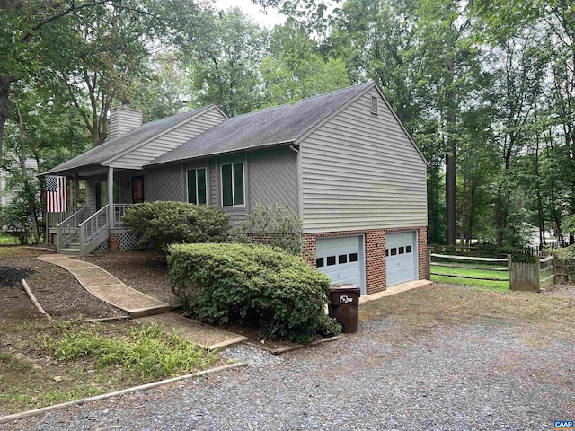 7 Englewood Dr, Palmyra, VA 22963 - view of home's exterior featuring a chimney, a garage, roof with shingles, covered porch, and brick siding