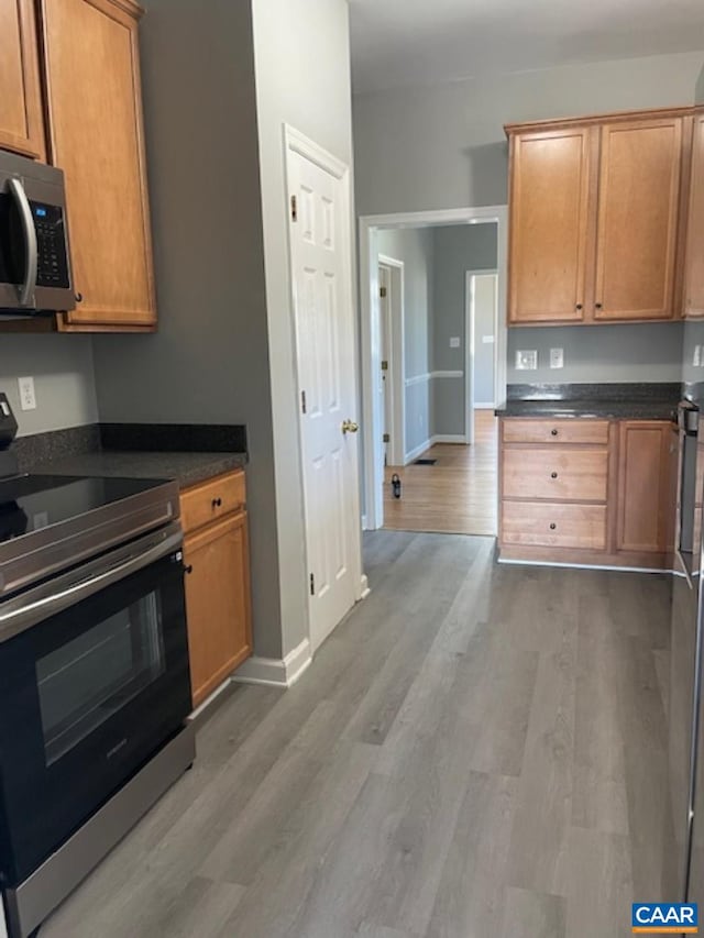 1414 Midland St, Charlottesville, VA 22902 - kitchen featuring appliances with stainless steel finishes, dark countertops, wood finished floors, and brown cabinetry