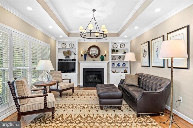 10042 Cedar Spring Ln, Culpeper, VA 22701 - living area featuring wood finished floors, a chandelier, crown molding, a fireplace with flush hearth, and built in shelves